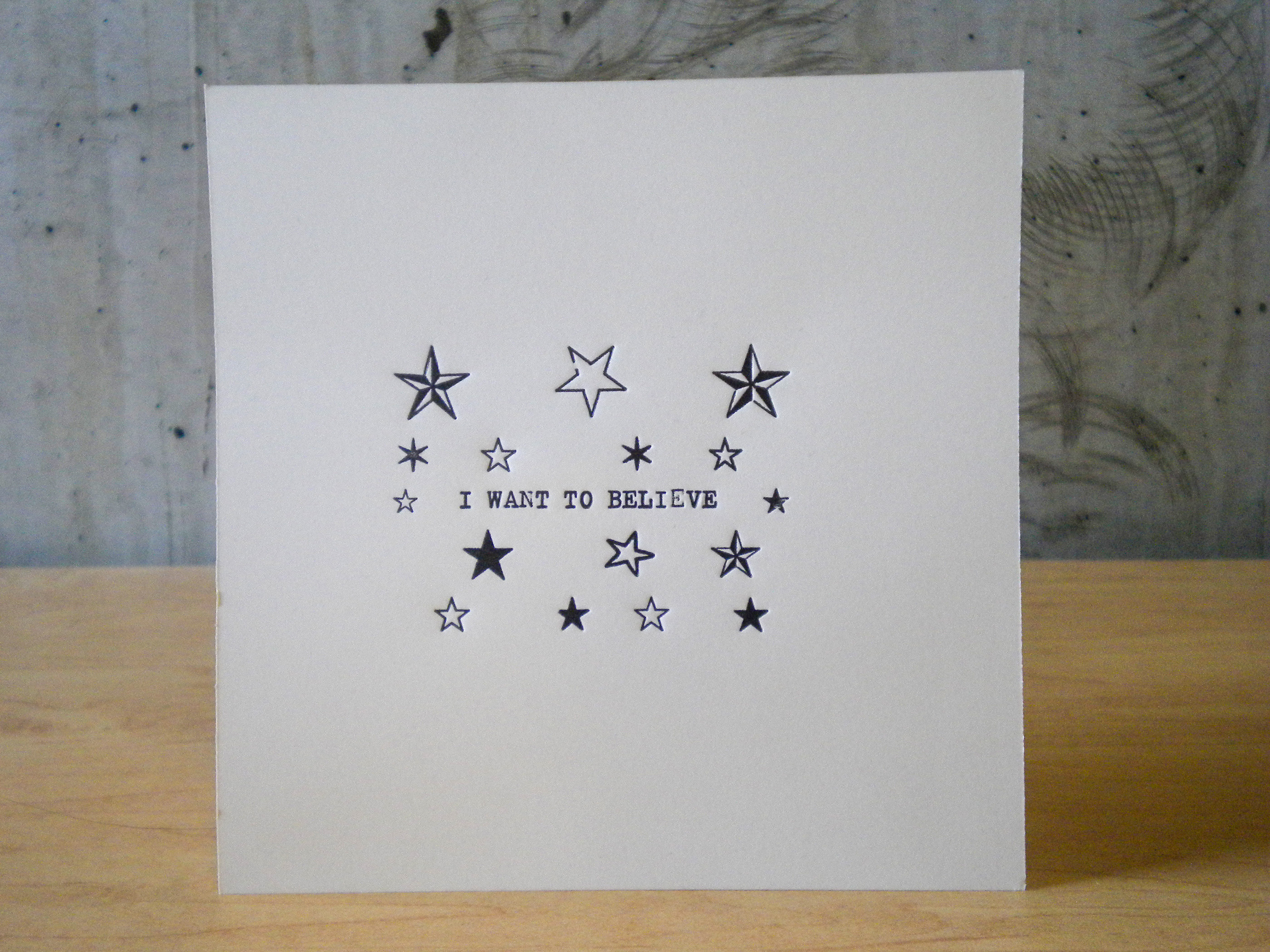 Letterpress printed phrase I want to believe surrounded by star ornaments
